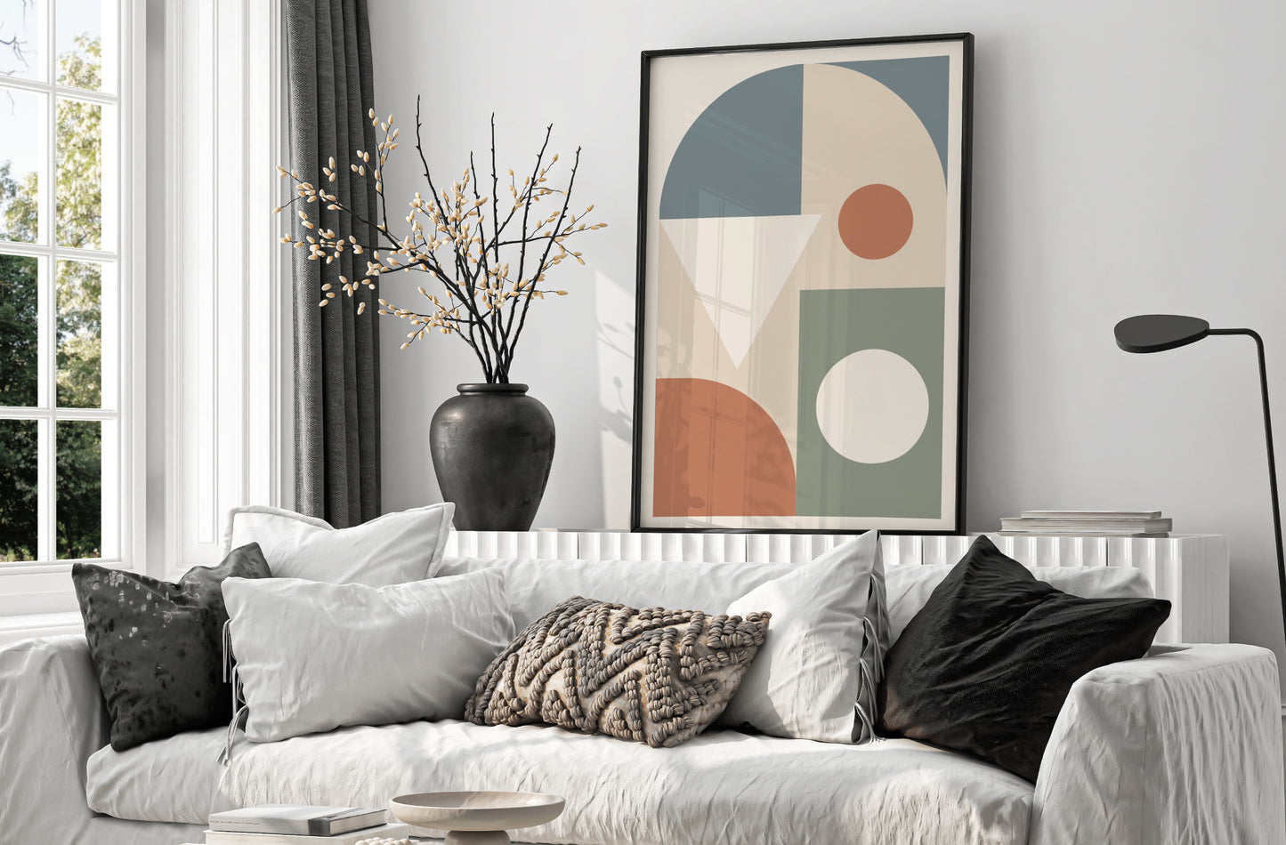 Living room with a white sofa, decorative pillows, and a colorful abstract art piece on the wall.
